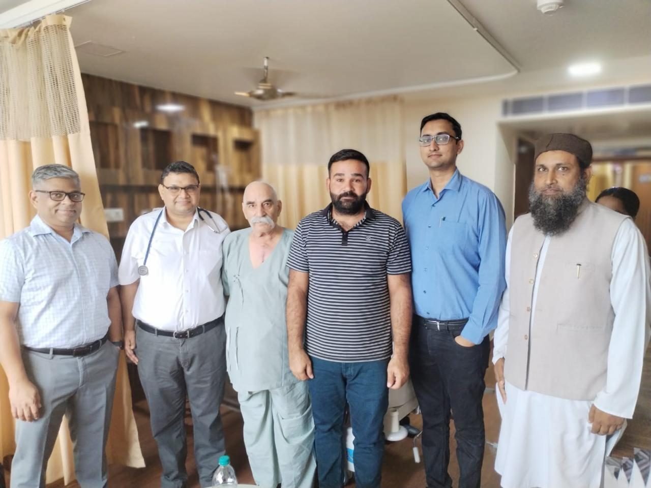 Six people standing together for a group photo in a hospital room